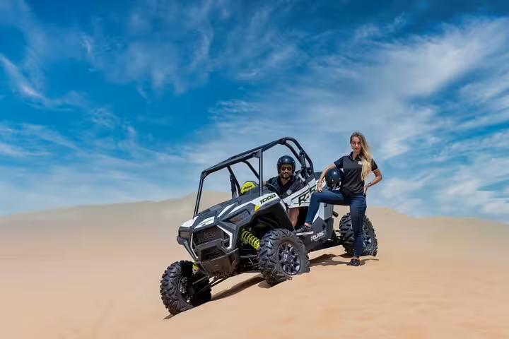 Adventurers enjoying a thrilling dune buggy ride in Dubai's desert landscape under a clear blue sky, ideal for off-road enthusiasts.