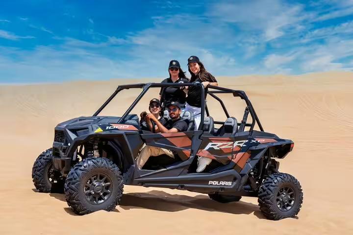 Group enjoying a thrilling dune buggy ride in the Dubai desert under a clear blue sky, perfect for adventure seekers.