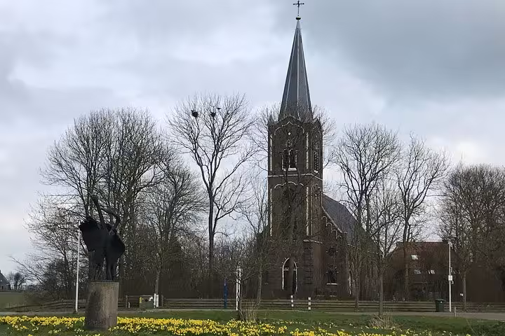 Historic Dutch church spire and spring daffodils, a Hidden Gems day tour stop from Amsterdam