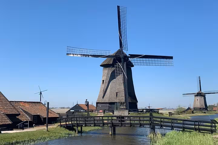 Iconic Dutch windmill by a wooden bridge and polder landscape, Hidden Gems Tour day trip from Amsterdam