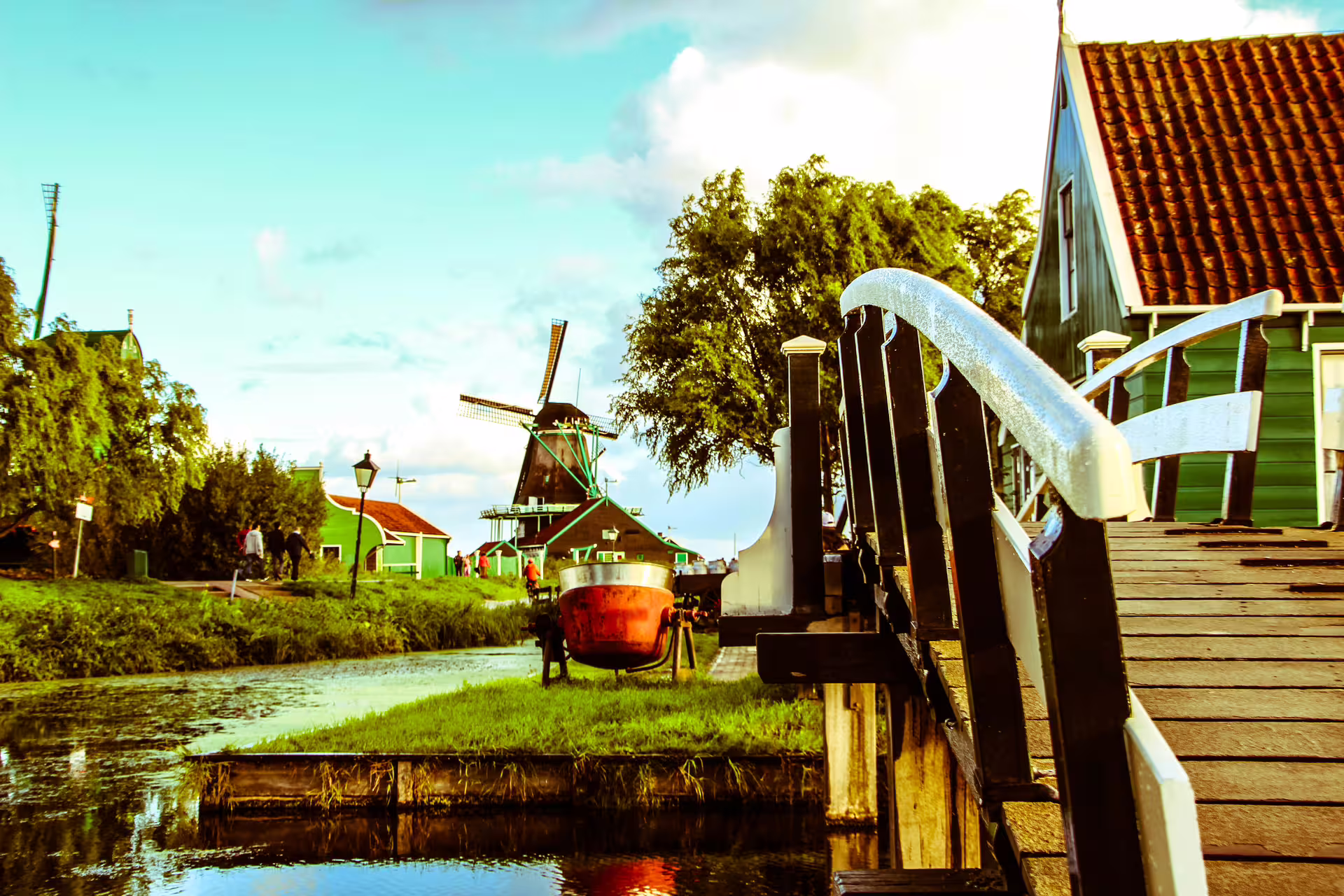 Scenic view of a traditional Dutch windmill and wooden bridge in Zaanse Schans, showcasing classic architecture and canals.
