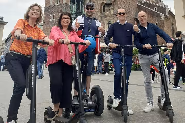 Group enjoying e-scooter tour in Krakow's Jewish Quarter, showcasing historic architecture and vibrant street life.