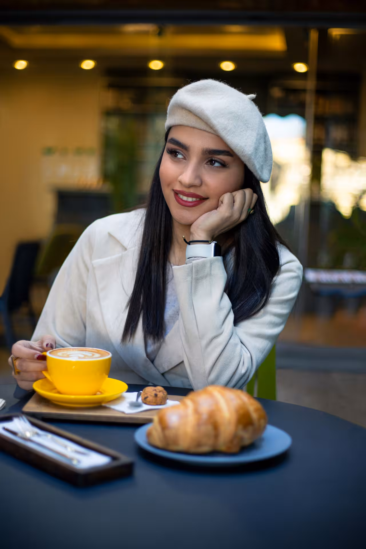 Woman savoring a morning coffee with a croissant at a cozy café, ideal for a relaxing start to an Italian day.