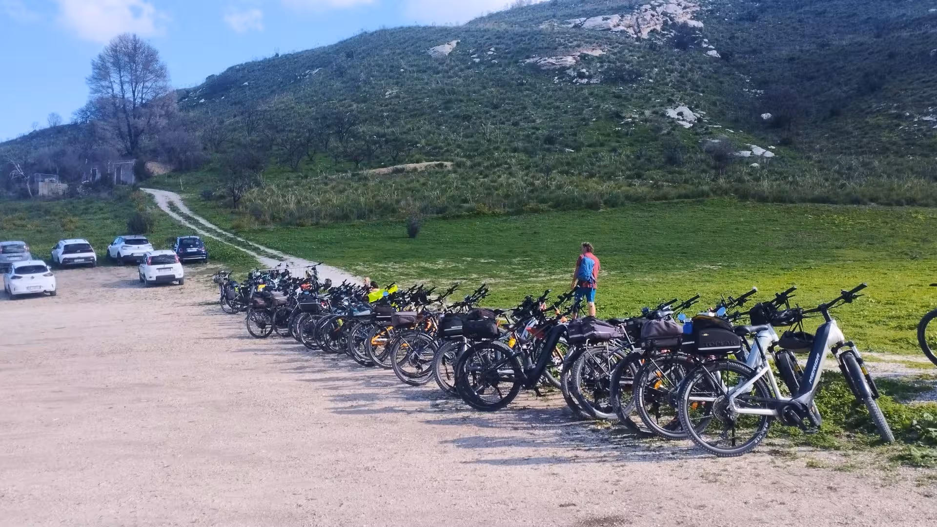 A line of ebikes parked at the starting point of a tour, with rolling hills as a backdrop near Castellammare del Golfo.