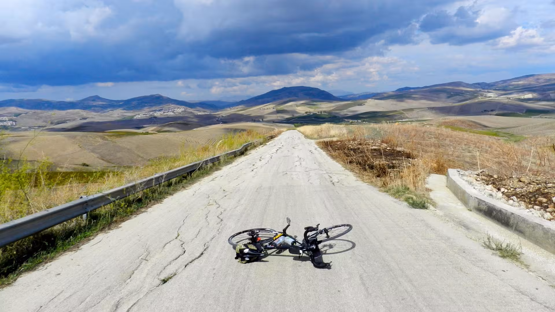 Abandoned bicycle on a rugged road with rolling hills, showcasing the adventurous route from Castellammare del Golfo to Segesta.