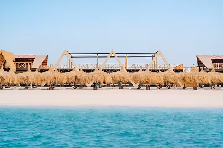 Eden Island Hurghada day trip beach club with thatched umbrellas, soft white sand and clear Red Sea water