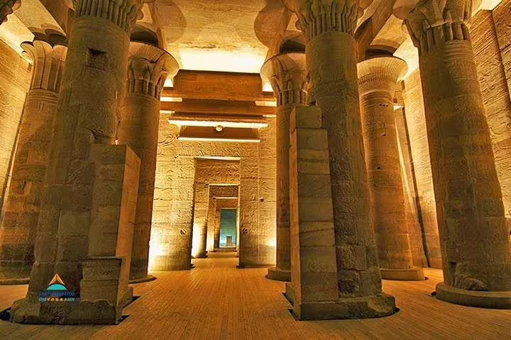 Edfu Temple hypostyle hall columns lit in golden light, visit on Luxor to Kom Ombo and Abu Simbel tour
