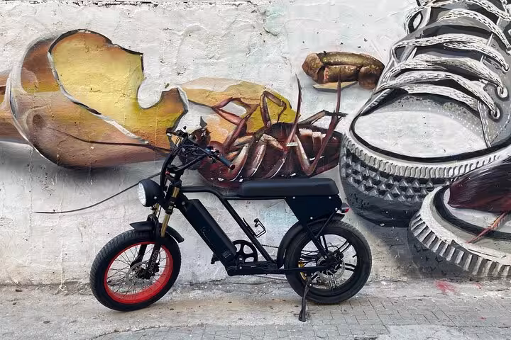 E-fat bike rental in Málaga parked by colorful street art mural, ideal for 10-hour self-guided city ride