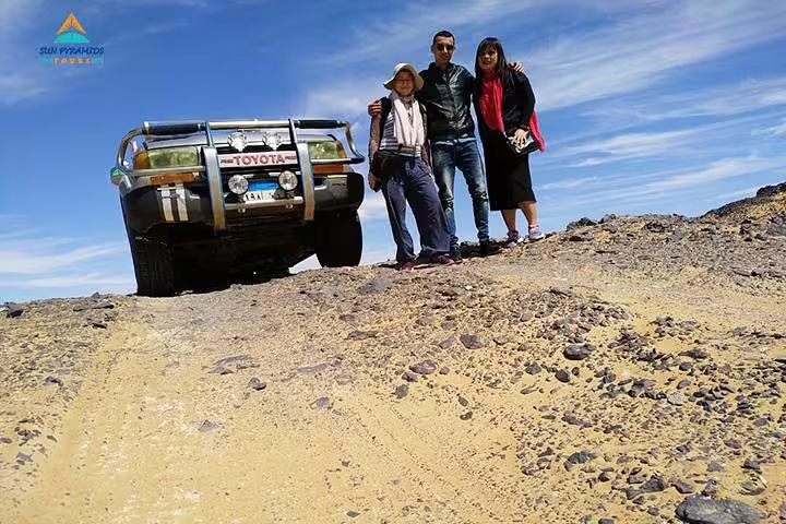 Group photo beside 4x4 in Egypt’s Western Desert, adventure day on 15-day Pyramids Luxor Aswan Oasis tour