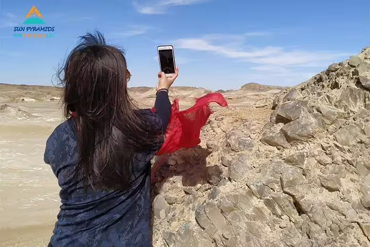 Traveler photographing Egypt’s Western Desert cliffs, part of 15-day Pyramids Luxor Aswan Oasis package