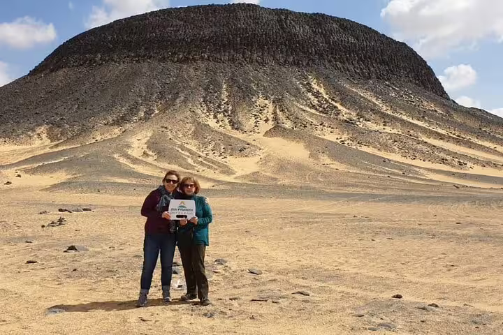 Travelers pose by a desert mountain on Egypt White Desert 5-day adventure tour with camping and Djara Cave