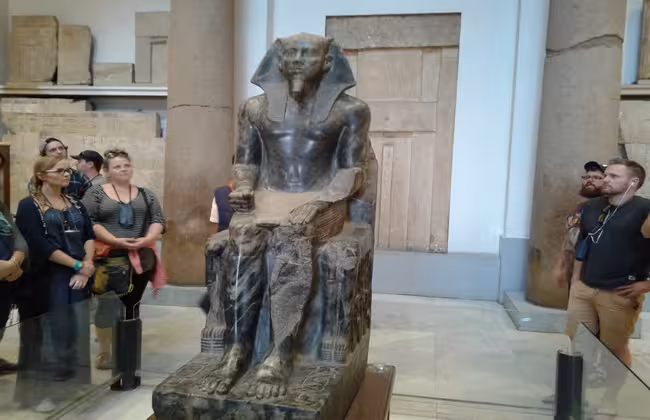 Visitors viewing a seated pharaoh statue at the Egyptian Museum Cairo during a private guided tour in Cairo