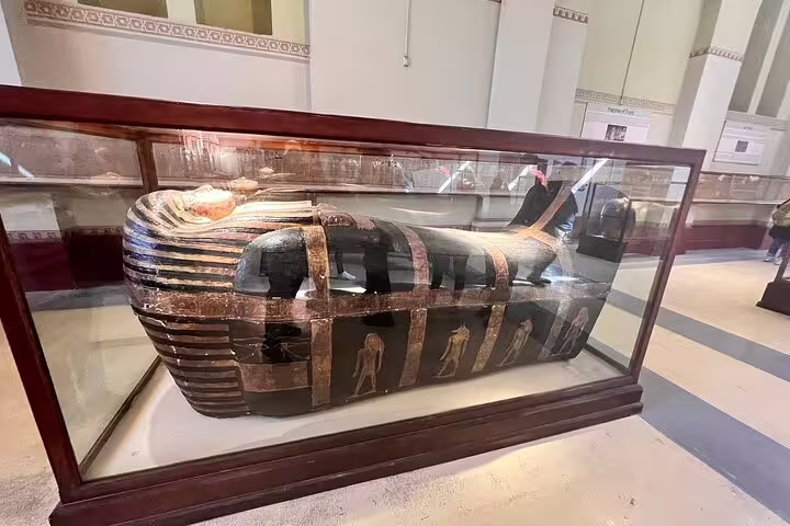 Painted ancient Egyptian sarcophagus in glass case at Cairo Museum, stop on Hurghada to Giza pyramids day trip