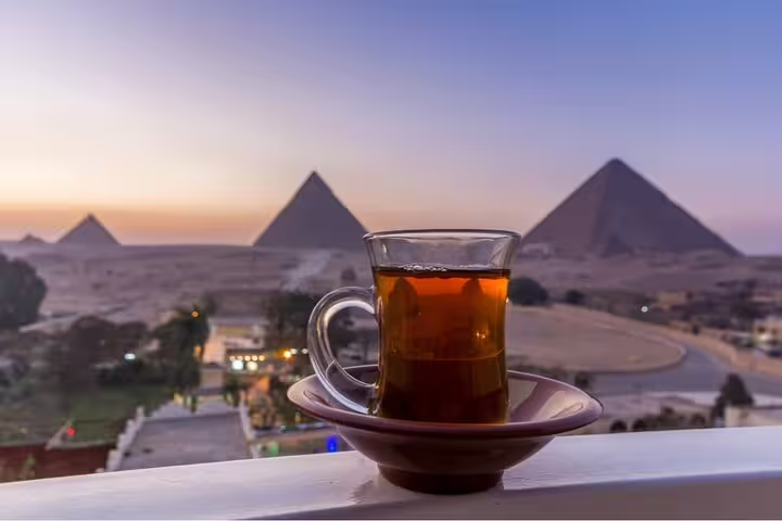 Glass of Egyptian tea on Great Pyramid Inn balcony with Giza Pyramids view at sunset lunch tour