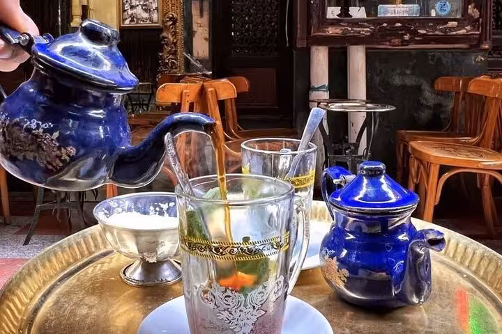 Traditional Egyptian tea poured from blue pot at Khan El Khalili cafe, authentic stop on Cairo Citadel tour