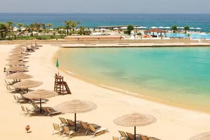 Sandy El Ain El Sokhna beach with umbrellas and calm Red Sea lagoon, ideal day tour from Cairo for swimming