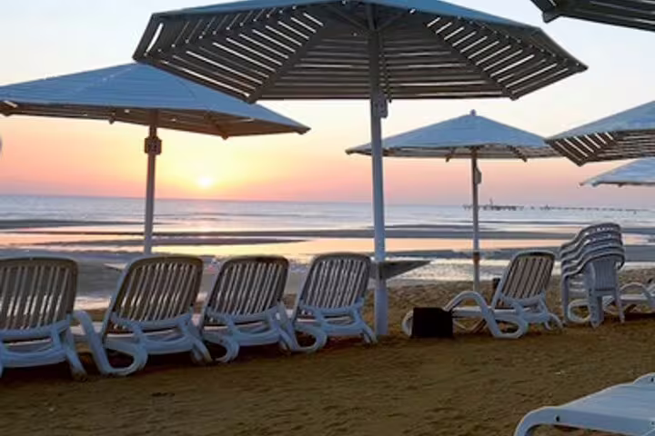 Sunset at El Ain Sokhna Red Sea with beach loungers and umbrellas on a private overnight tour from Cairo