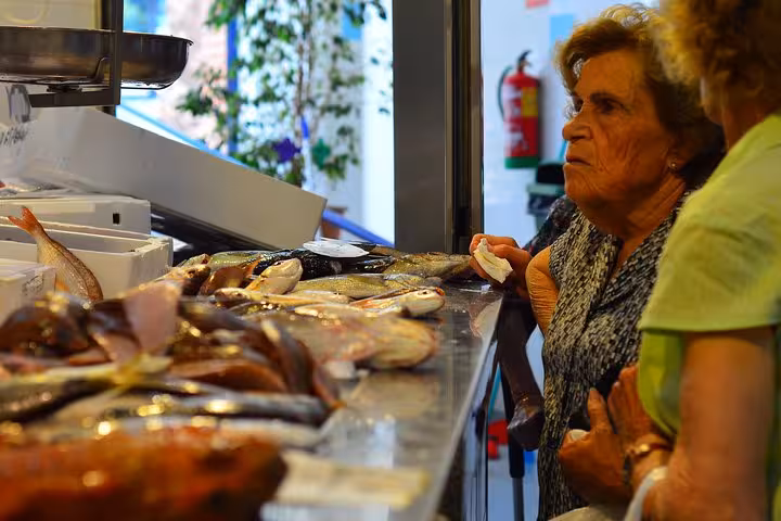 Elderly women examining fresh seafood at a local market on the Taste of Marbella Food and Market Tour.