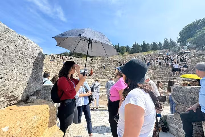 Guide with umbrella leads cruisers through Ephesus amphitheater on Kusadasi shore excursion to Mary’s House