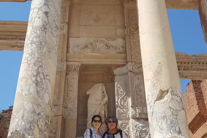 Travelers at Ephesus ancient ruins by marble columns and statue on an Izmir cruise port shore excursion