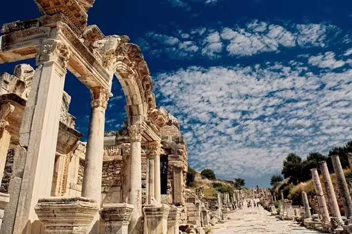 Explore the ancient ruins of Ephesus with stunning columns and arches under a vibrant sky on a private tour from Kusadasi Port.
