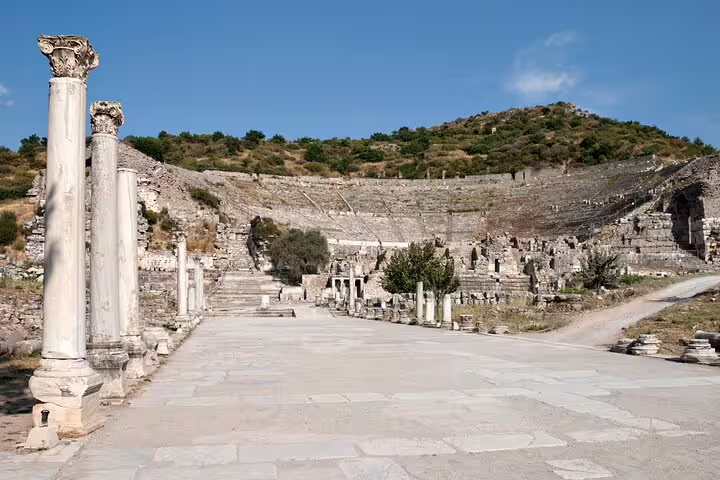 View of the ancient theater in Ephesus, surrounded by lush greenery and featuring prominent marble columns.