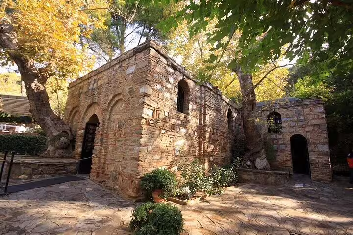 The historic House of the Virgin Mary in Ephesus surrounded by lush greenery and stone pathways.