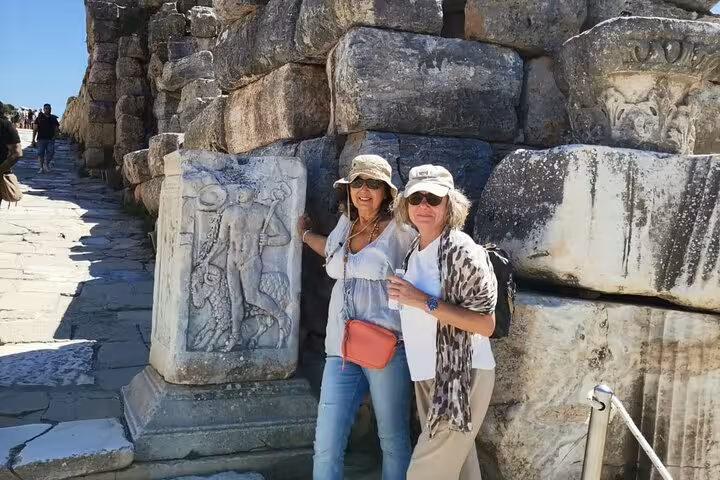 Visitors beside carved marble relief in Ephesus ruins on private cruise shore excursion, skip-the-line tour