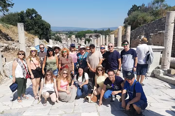 Group of cruise passengers on skip-the-line Ephesus tour walking the marble street among ancient columns