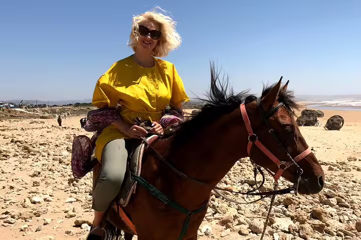 Traveler horseback riding on Essaouira beach, Morocco, scenic Atlantic coast experience on a walking tour