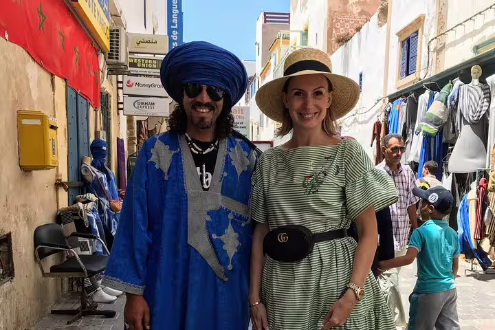 Traveler and local guide in Essaouira medina souk on a private Morocco walking tour, colorful market street
