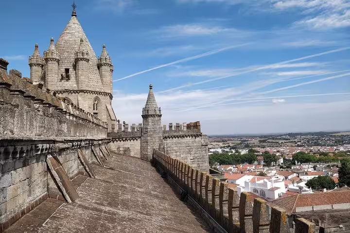 Évora Cathedral's ancient stone architecture overlooks the cityscape, captured on a sunny day during the full-day tour from Lisbon.