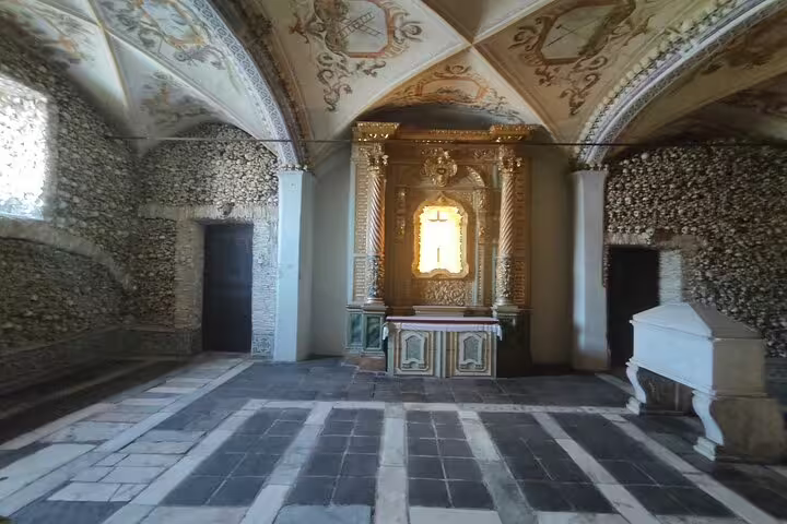 Interior view of the Chapel of Bones in Évora, showcasing walls adorned with human skulls and intricate architectural details.