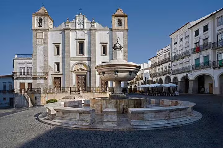 Discover the charming Praça do Giraldo with its iconic fountain and historic church in Évora, featured on the Lisbon to Monsaraz tour.