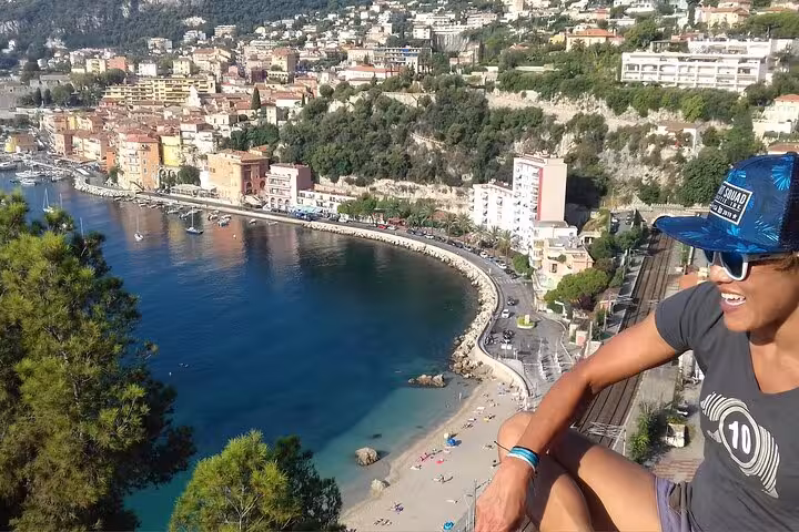 Traveler admires the stunning coastal view of Eze Village with its vibrant buildings and serene beach.