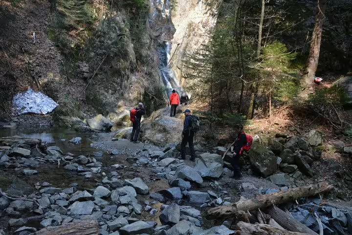 Hikers with backpacks exploring rocky canyon with waterfall on Fagaras hiking tour