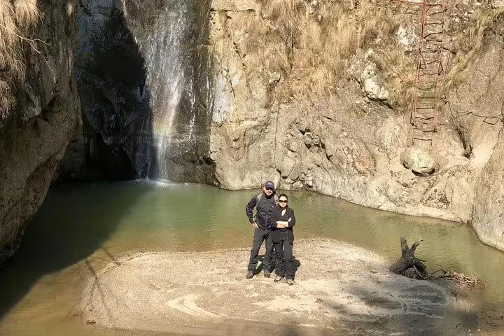 Couple standing by a waterfall pool in Fagaras mountains during a private hiking tour