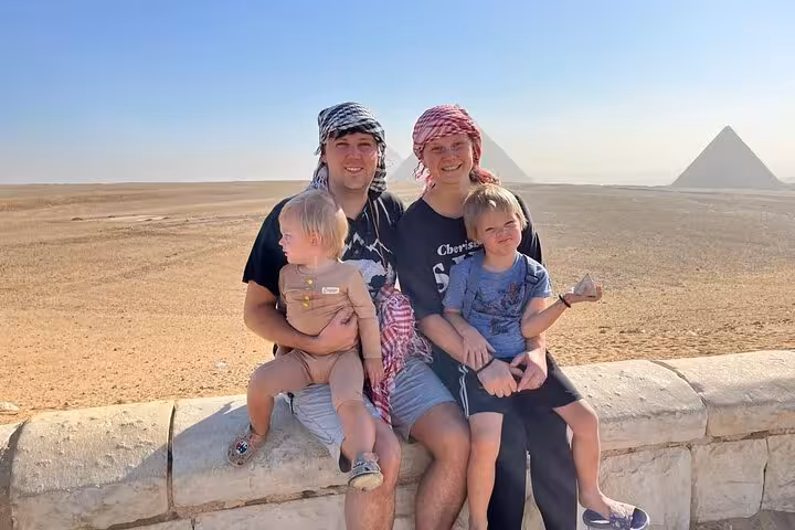 Family sitting by the Giza Pyramids desert view, a highlight of VIP Giza Pyramids Wonders and GEM tour Cairo