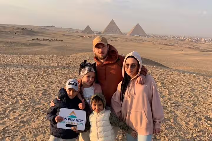 Family photo at Giza Pyramids during private no hidden cost tour, desert viewpoint with Great Pyramid behind