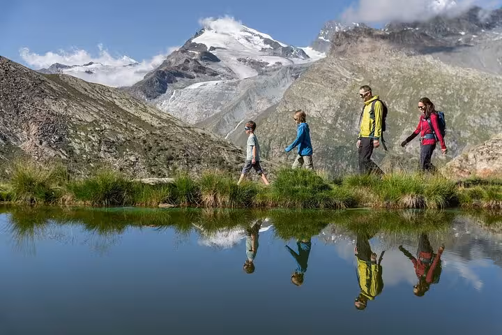 Family hiking by an alpine lake with glacier views, a hidden gem on a Swiss Alps tour from Zurich Airport
