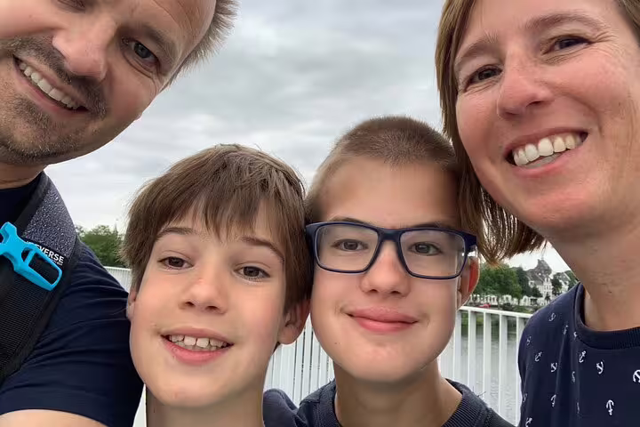 Family selfie on a riverside walkway during a London e-scavenger hunt, enjoying a self-paced city adventure