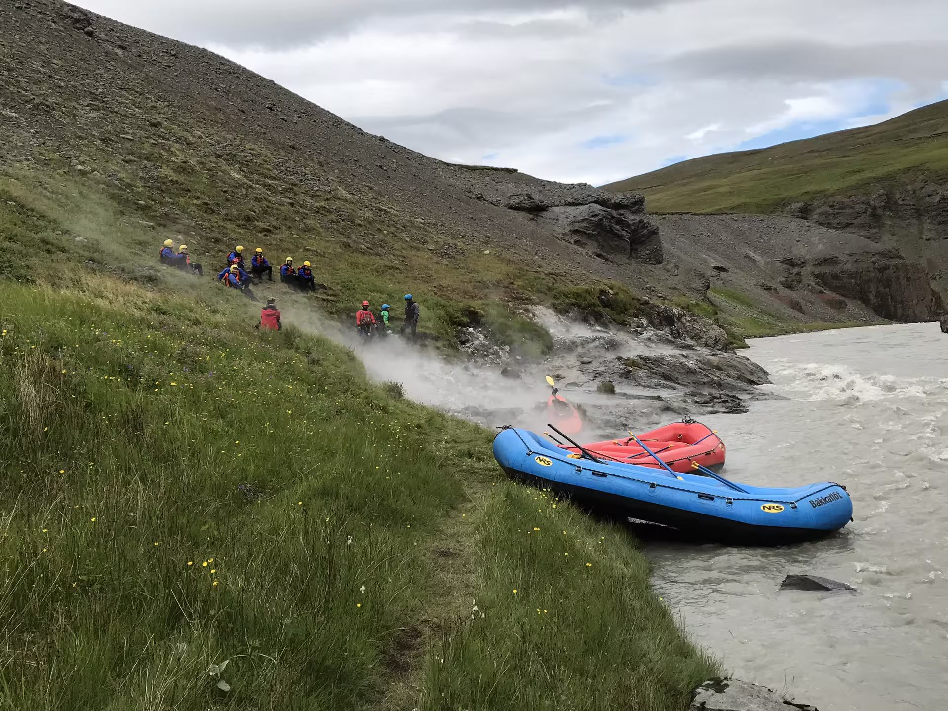 Family enjoying a thrilling river rafting adventure with inflatable rafts on a scenic, rugged riverbank surrounded by lush greenery.
