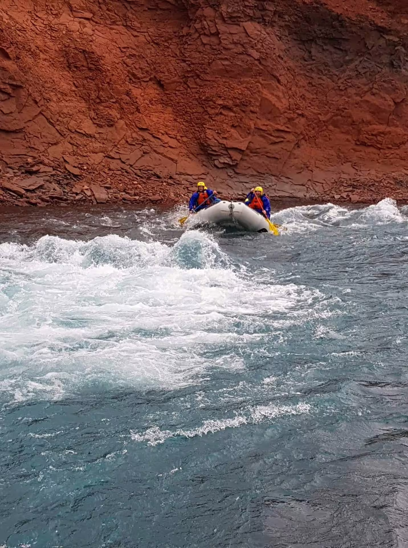 Family enjoying an exhilarating river rafting adventure through exciting rapids, surrounded by stunning red rock cliffs.