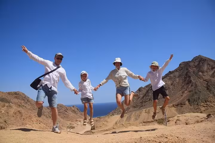Family jumping in Sinai desert viewpoint on Super Colored Canyon jeep tour and Blue Hole trip from Sharm El Sheikh