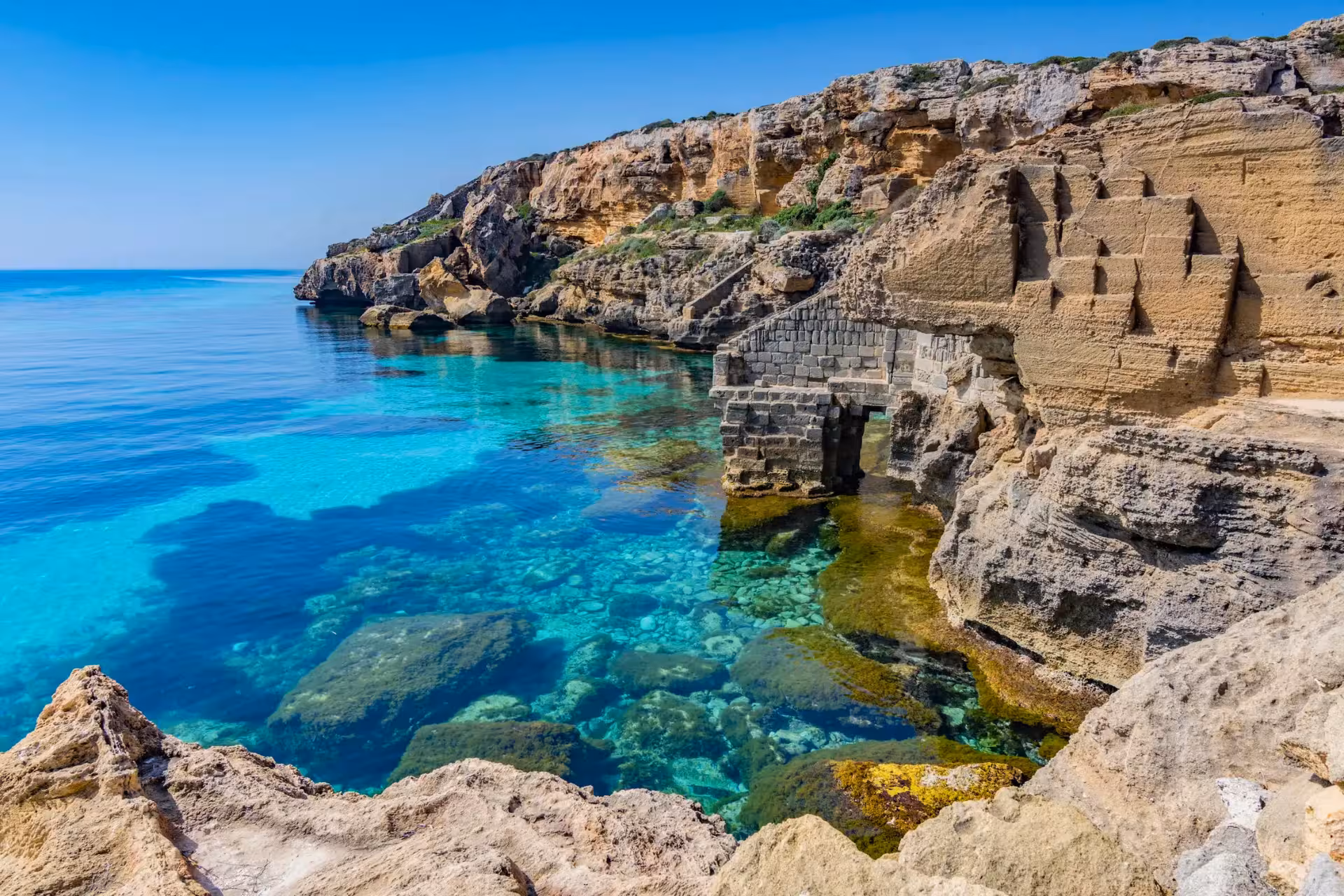 Crystal-clear bay and rocky cliffs in Favignana, photo from Egadi Islands dinghy excursion with lunch from Trapani