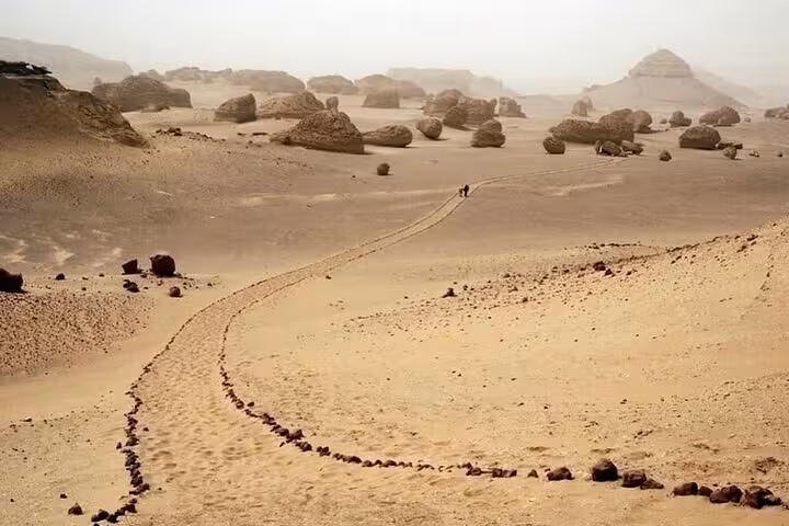 Winding desert trail through Fayoum’s Wadi El Hitan rock formations on a nature and history tour in Egypt