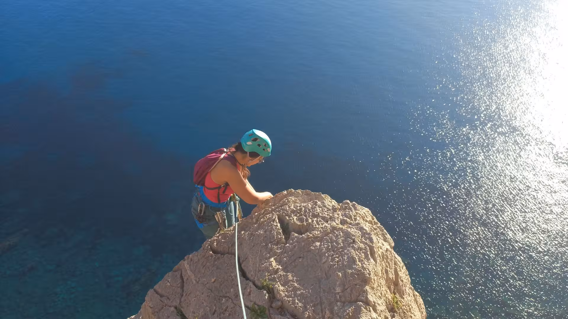 Female climber ascends a rocky peak with breathtaking ocean views on the Masua cliff in Nebida.