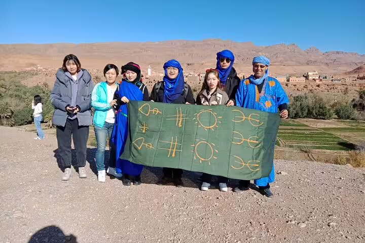 Travelers with Berber guides holding banner in Dades Valley, highlight of 3-day Fes to Marrakech desert tour