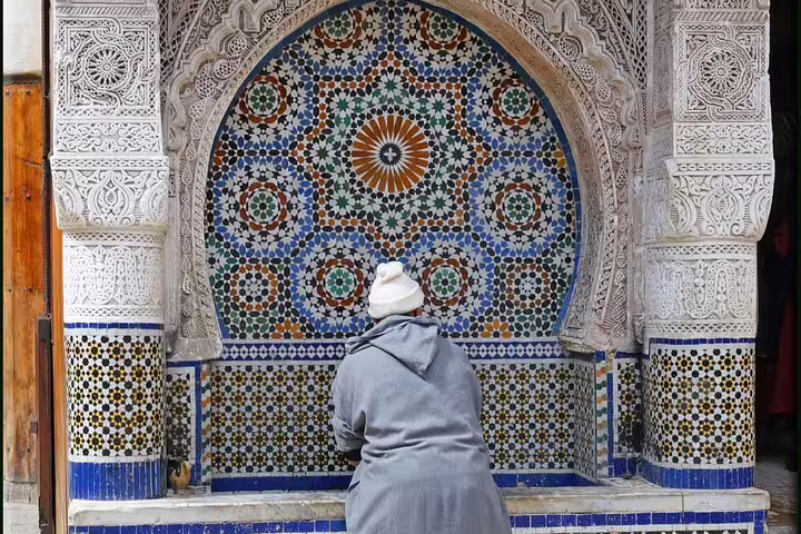 Traveler at ornate zellige mosaic fountain in Fes Medina, Morocco, exploring artisan tiles on a private tour