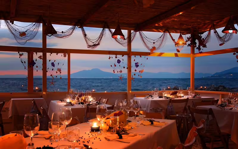 Romantic seaside dinner setup in Ischia at dusk for Festa di Sant’Anna boat and fireworks experience on the bay